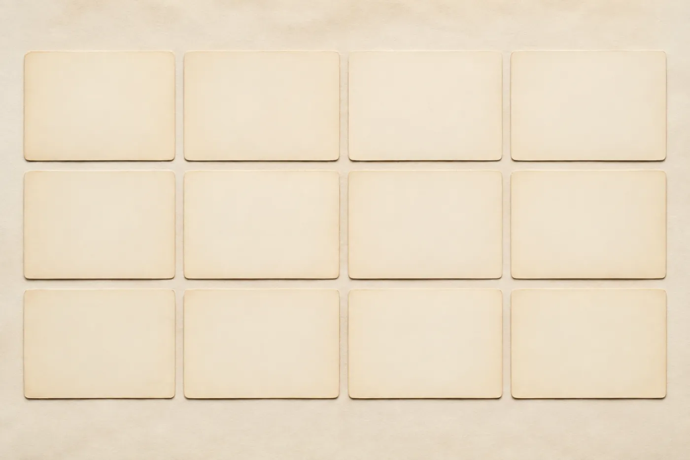 Twelve blank cream cards arranged in a precise grid on warm off-white paper.
