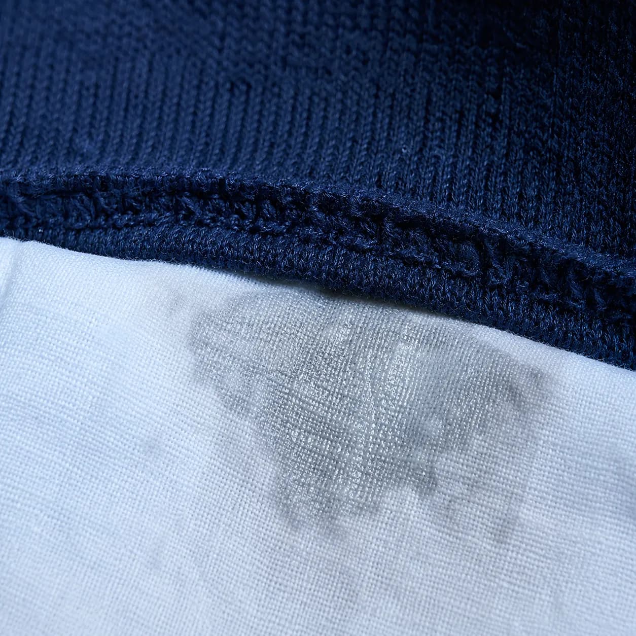 A damp white cotton cloth pressed flat against the inside seam of a deep indigo knit.